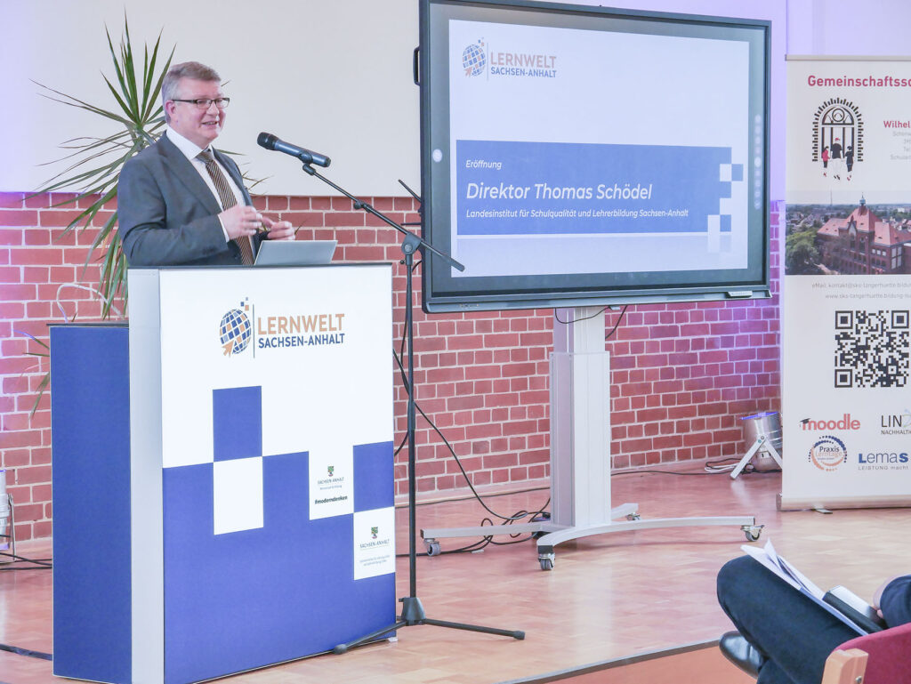 Direktor Thomas Schödel vom LISA spricht am Rednerpult auf einer Bühne im Veranstaltungssaal bei der Eröffnung des Projektstarts „Lernwelt Sachsen-Anhalt“ in der Wilhelm-Wundt-Gemeinschaftsschule Tangerhütte.
